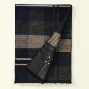 Détail de l'écharpe à carreaux avec franges denses et motif classique en bleu marine et gris