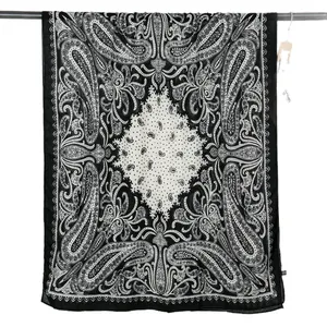 Lightweight black and white paisley print scarf displayed on a horizontal hanging bar