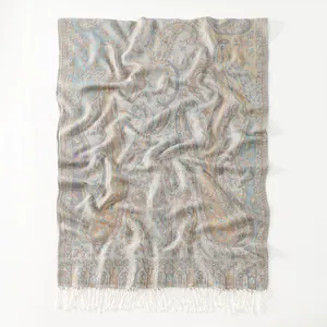 Detailed view of paisley pattern pashmina scarf with soft blue and beige tones and white tassels