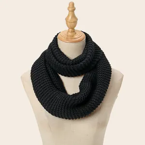 Detail of chunky black knit texture and vertical ribbed pattern on an infinity scarf