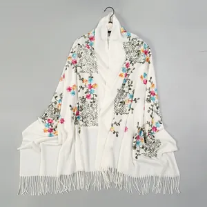 Detailed embroidery of colorful flowers on a soft off-white cashmere-like shawl with fringe