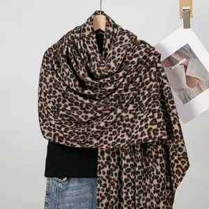 Classic thick leopard print scarf draped over a black sweater and blue jeans