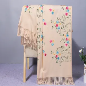 Detail of beige cashmere shawl showing floral vine embroidery and fringe tassels