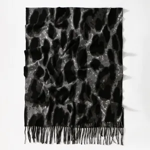 Detailed close-up of cashmere-like leopard print scarf with soft gray and black fringes