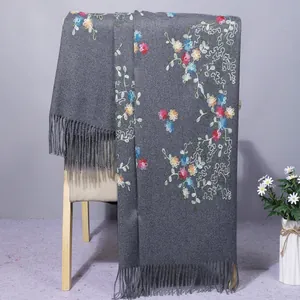 Close-up of floral embroidery on a dark gray cashmere shawl with elegant fringe details