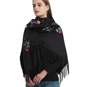 Close-up of intricate colorful floral vine embroidery and long tassels on black shawl