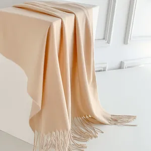 Dettaglio di sciarpa color crema effetto cashmere con frange morbide e trama pregiata