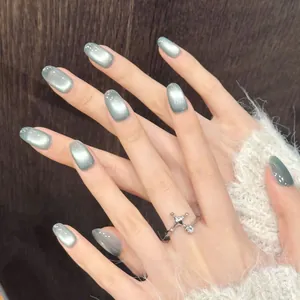 Ongles cat eye gris-vert élégants avec bague étoile argentée sur fond bois sombre