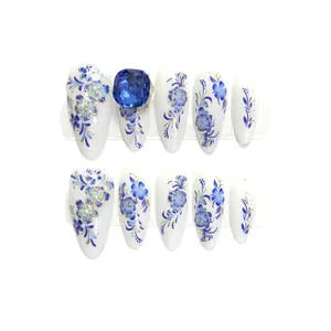 Faux ongles style porcelaine bleue et blanche avec bordure dorée et strass bleu