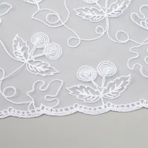 Close-up of white lace triangle shawl featuring delicate cherry embroidery and scalloped edges