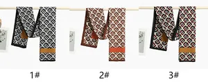 Three geometric print scarves in neutral tones displayed on a minimalist wooden rail