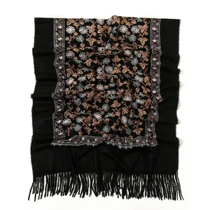 Detailed close-up of vintage floral embroidery and tassels on a soft black shawl