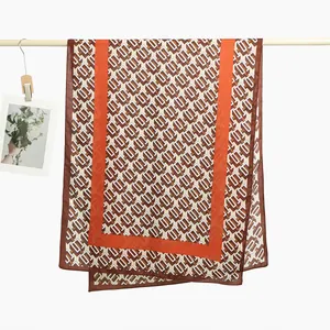 Detail of printed scarf featuring geometric patterns and vibrant orange borders