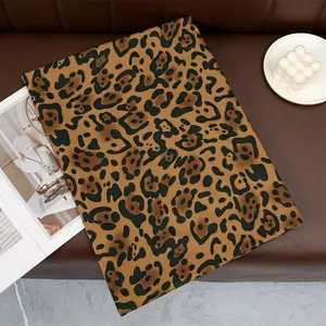 Detailed view of leopard print cotton scarf fabric on brown leather with magazines