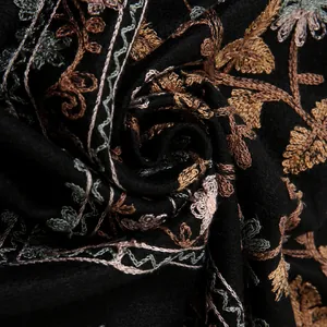 Close-up of intricate ginkgo leaf embroidery on soft black cashmere-feel fabric scarf