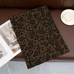 Detail of leopard print scarf with brown animal pattern on leather texture background