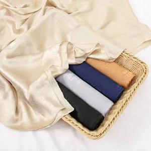 Detailed view of high-gloss silk satin scarves with embossed snakeskin texture in a basket