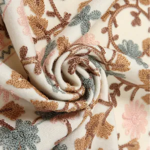 Close-up of elegant ginkgo embroidery on soft beige cashmere-like fabric scarf