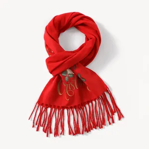 Detail of red Christmas scarf with gold lettering, green holly motifs and fringe edges