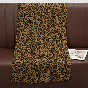 Fashionable leopard print cotton shawl displayed on a leather sofa with warm home decor