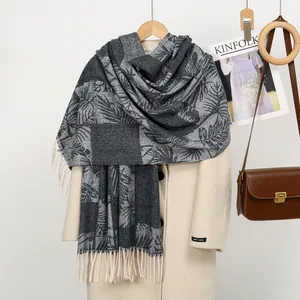 Macro detail of leaf pattern jacquard texture and beige tassels on cashmere-feel scarf