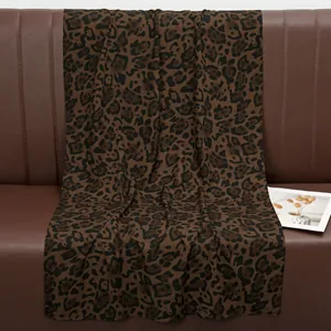 Close-up of leopard print cotton scarf with soft texture draped on a leather sofa