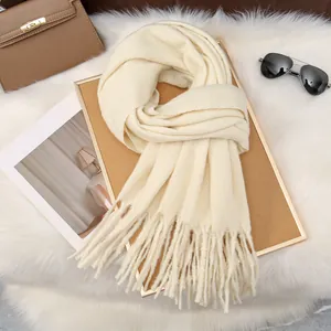 Detail of soft cream white milk velvet knit scarf with long tassels on a stylish background