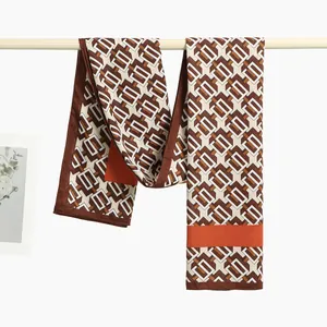 Detail of printed silk scarf with geometric chain patterns and bright orange borders