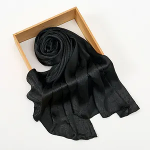 Detail of black silk-like scarf with snake skin pattern draped on a wooden display
