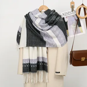 Detail of geometric knit shawl with black and purple patterns and long white tassels