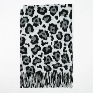 Detail of leopard print knit scarf featuring soft cashmere-like fabric and fringe edges