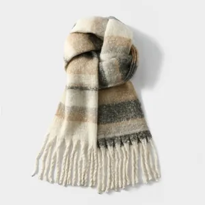 Detail of a thick plaid cashmere scarf featuring neutral earth tones and long fringe trim