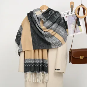 Detailed view of geometric jacquard patterns and white tassels on cashmere-like scarf