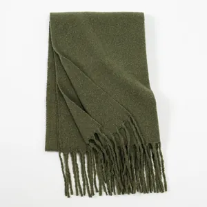 Close-up of dark green winter scarf featuring soft plush texture and elegant long fringe