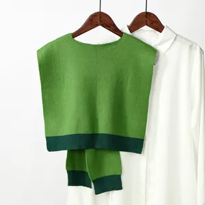 Detail of green knit vest with contrast ribbed hem over a white collared shirt
