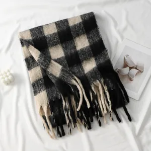 Dettaglio di sciarpa a quadri bianchi e neri in finto cashmere con nappe e frange
