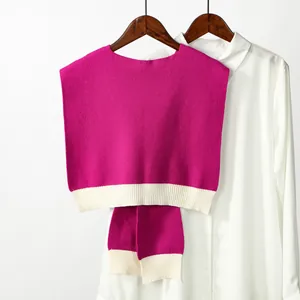 Close-up of pink houndstooth knit shawl with white ribbed hem on a wooden hanger
