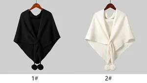 Detailed knit texture of solid color capes with decorative pom-poms and front tie design