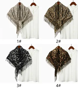 Four leopard print scarves with fringes displayed on hangers over white shirts
