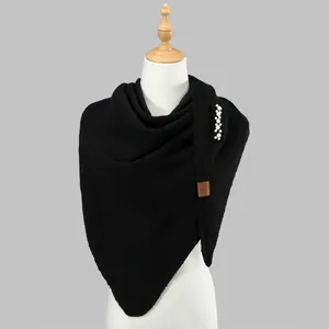 Elegant black knitted triangle shawl with decorative pearl brooch on a display mannequin