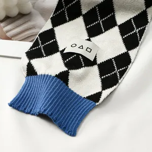 Detail of blue ribbed knit cuff on black and white argyle pattern shawl with fabric tag