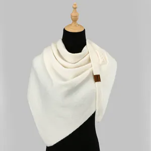 Close-up of white knitted shawl with pearl decorations and brown leather label