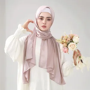 Detail view of pink pleated hijab scarf with metallic threads and floral accent