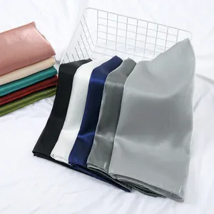 Close-up of elegant glossy silk scarves in multiple colors neatly folded in a white basket