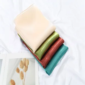 Detail of shimmering silk scarves showing fine texture and glossy finish in multiple colors