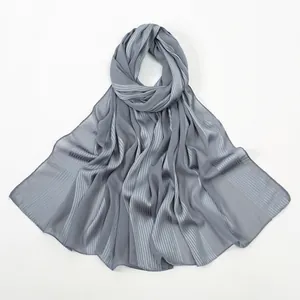Close-up of dark grey linen-feel scarf showing vertical pleated texture and sheer fabric