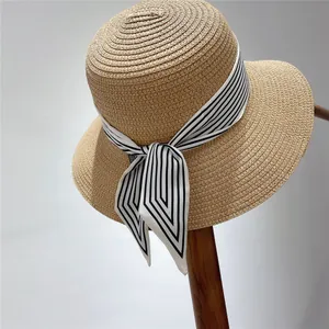 Detail of flat top straw hat with a black and white striped ribbon bow decoration