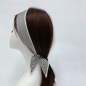 Detailed view of a striped skinny silk scarf tied into a bow on a hairstyle