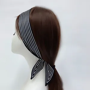 Detail showing the black and white striped satin hair scarf tied on a ponytail with drapes