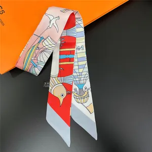 Silk twilly scarf with hot air balloon pattern on luxury orange packaging background
